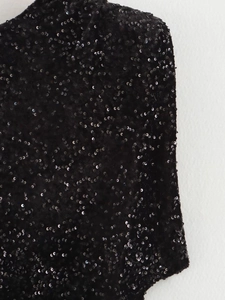 Détail rapproché des paillettes noires scintillantes sur une robe de soirée élégante