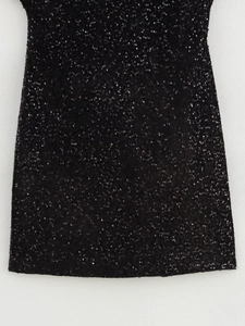 Gros plan des paillettes noires sur une robe ajustée avec texture détaillée et fini brillant