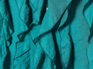 Close-up of dark teal chiffon fabric showing layered ruffles and detailed stitching