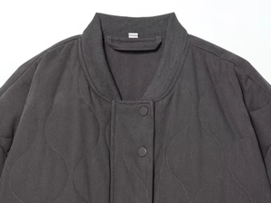 Detailed close-up of dark grey quilted bomber jacket with wave stitching and ribbed collar