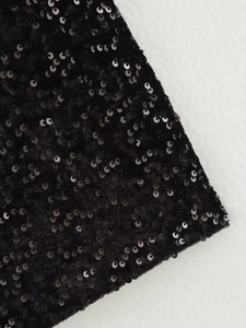Gros plan sur un tissu à paillettes noires avec texture métallique et fini brillant