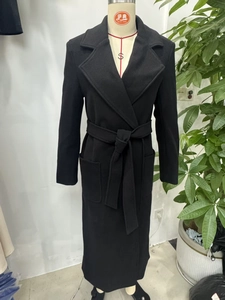 Close-up of black woolen coat for women with matching waist belt and large pockets