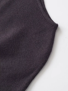 Dettaglio dell'abito in maglia viola scuro che mostra la trama del tessuto e la cucitura