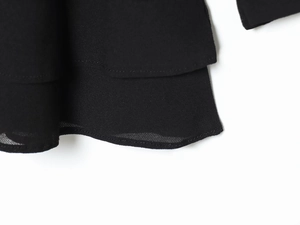 Detail des gestuften schwarzen Kleidsaums aus leichtem Stoff mit feinen Rollkanten-Besatz
