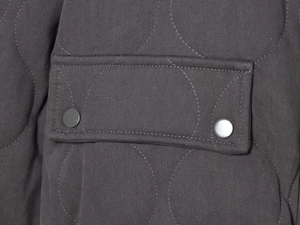 Detail of dark grey onion quilted jacket with twin metal snap buttons on pocket flap