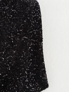 Détail macro des paillettes noires scintillantes sur la robe montrant la texture