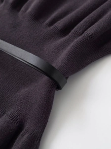 Dettaglio della trama in maglia viola scuro e cintura sottile in pelle nera minimalista
