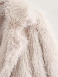 Detailed macro view of the soft faux fur texture on this cream winter coat for women