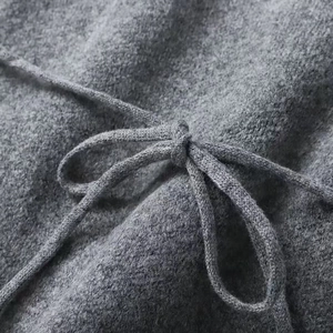 Close-up of grey knit cardigan sweater featuring a soft texture and matching waist tie