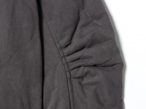 Macro view of deep gray quilted jacket fabric featuring onion wave stitching and elastic seam