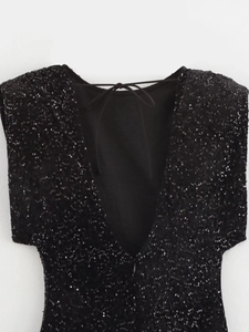 Détail d'une robe noire à paillettes avec col en V profond et lien à nouer dans le dos