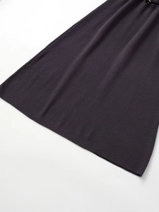 Dettaglio ravvicinato della maglia grigio scuro con sottile cintura nera ed elegante fibbia