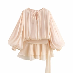 Macro shot of apricot pleated chiffon dress detailing tiered ruffle hem and bishop sleeves