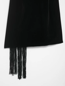 Detailed view of the asymmetrical black velvet hemline featuring elegant long fringe trim