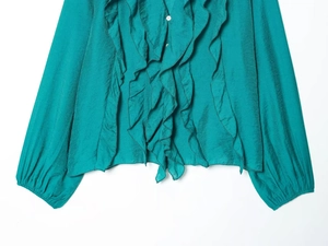 Detailed view of layered ruffles and white buttons on a teal long sleeve summer blouse