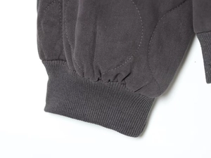 Detailed view of dark grey quilted fabric and ribbed cuffs on the pilot jacket