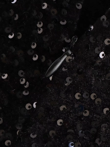 Détail d'une robe à paillettes noires avec une fermeture éclair invisible de qualité