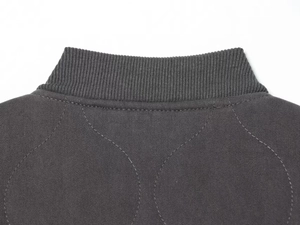 Close-up of ribbed knit collar and quilted pattern on dark grey bomber jacket
