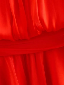 Detail of red pleated chiffon fabric showing fine texture and draped asymmetric hem