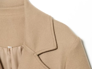 Detail shot of camel wool coat showing smooth silk lining and premium shoulder stitching