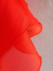 Detail of red summer dress featuring multi-layered ruffled hem and fine stitching