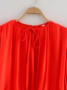 Detail of red chiffon top with a pleated texture, tie-neckline and size M label