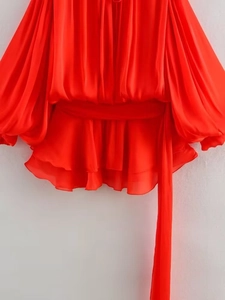 Detailed view of red pleated chiffon fabric with ruffled hem and flowing tie belt