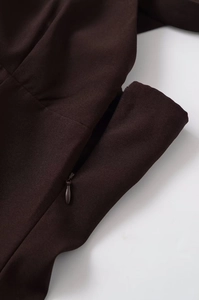 Detail of invisible teardrop zipper on the back of a dark brown fashionable V-neck dress