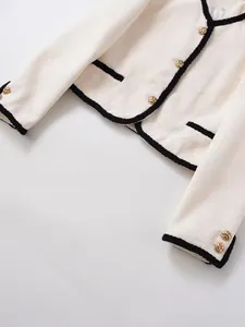Detail of tweed fabric texture and golden twisted metal button on ivory jacket