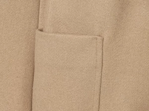 Detail of premium camel wool coat featuring a neat patch pocket and high-quality stitching