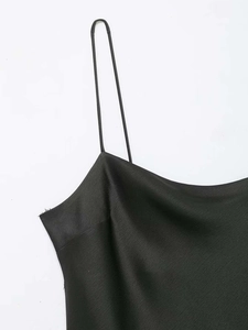 Détail de la robe en satin noir avec bretelles fines et texture de soie brillante