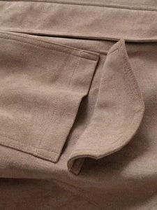 Macro view showing the flap pocket detail and soft suede texture of the brown jacket