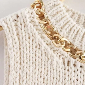 Creamy knit sweater featuring asymmetric hem and chunky gold chain link hardware detail