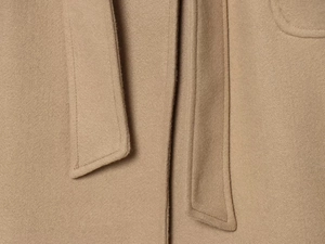 Close-up of premium camel wool fabric texture and waist belt stitching detail on the coat