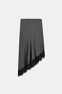 Detalle de falda midi de satén gris oscuro con dobladillo asimétrico y encaje negro fino