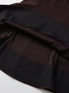 Detailed close-up of dark brown dress hem showing fine stitching and black lining fabric