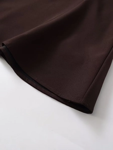 Detail of a chocolate brown dress hem with neat stitching and black lining fabric