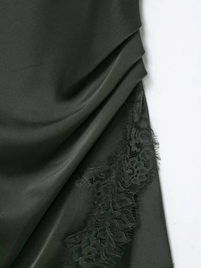 Détail de la robe en satin vert foncé avec tissu plissé et bordure en dentelle cil fine