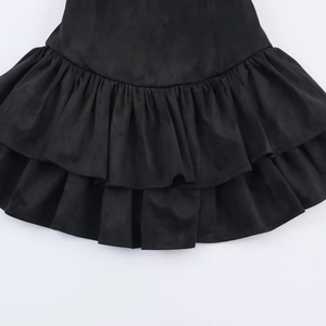Detail of tiered ruffle hem and pleated matte fabric on black mini dress