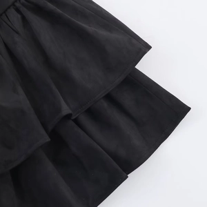 Detail view of tiered ruffles and precise stitching on black matte fabric dress