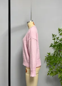 Detail view of pink crew neck knit sweater with ribbed cuffs and drop shoulder design