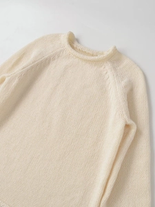 Detailed close-up of cream chunky knit sweater featuring raglan sleeves and ribbed crewneck