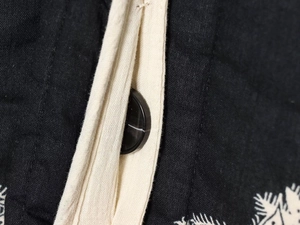 Detail shot of monochrome botanical embroidery and premium marble-patterned button on jacket