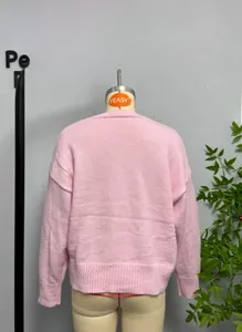 Back view of pink crewneck knit sweater featuring ribbed cuffs and drop shoulder design