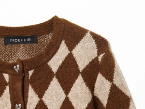Makroaufnahme einer Argyle-Strickjacke mit herzförmigen Silberknöpfen und Markenetikett