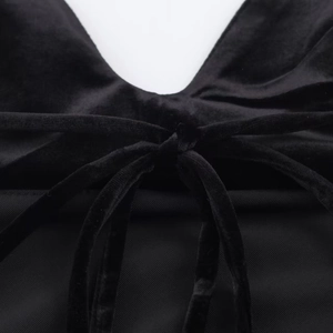Detailed close-up of the black satin dress featuring a velvet ribbon tie-up design