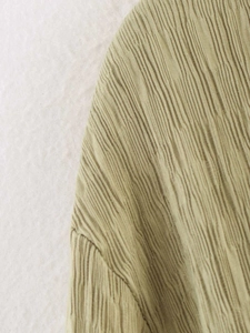 Détail du tissu kaki présentant des motifs plissés verticaux et une texture élégante