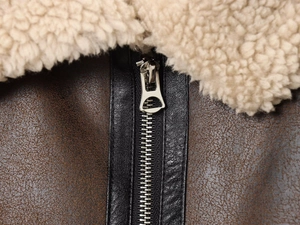 Detail of silver metal zipper and faux shearling collar on a vintage brown jacket