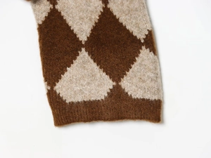 Makroaufnahme von Rautenmuster-Strickwaren mit weichen braunen Fasern und Rippbündchen