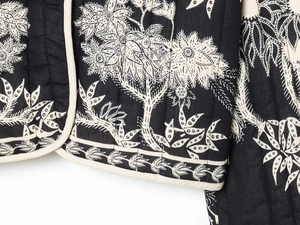 Detail of black and white floral embroidery and quilted texture on cotton jacket